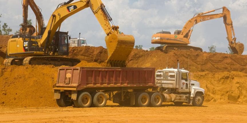 Heavy equipment loading tipper trucks at a construction site