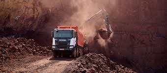 Tipper truck in active haulage with dust from loading